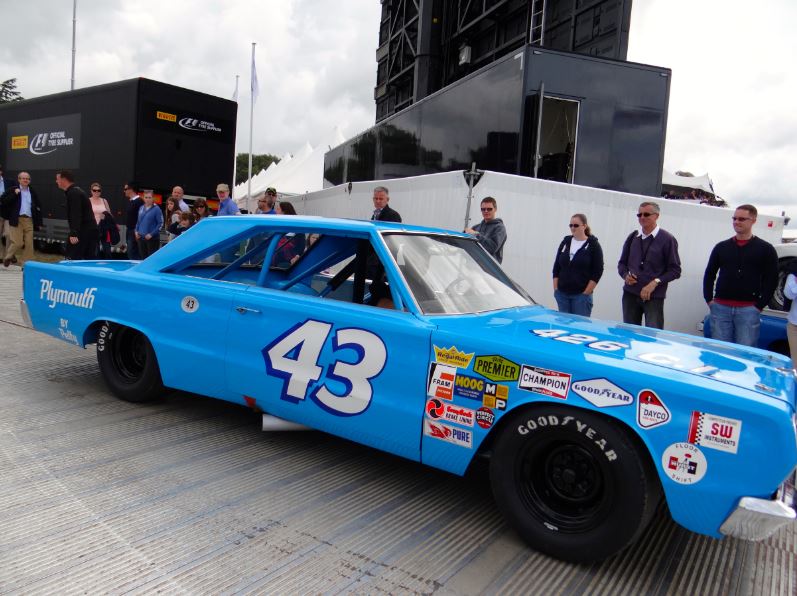 several people looking at the blue Plymouth car