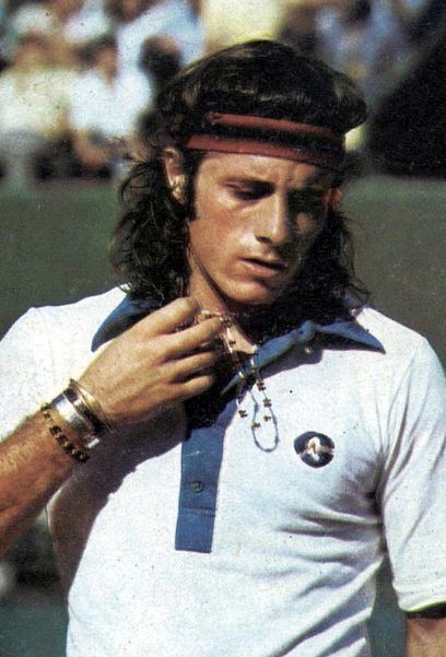 Guillermo Vilas wearing his tennis jersey and holding a necklace