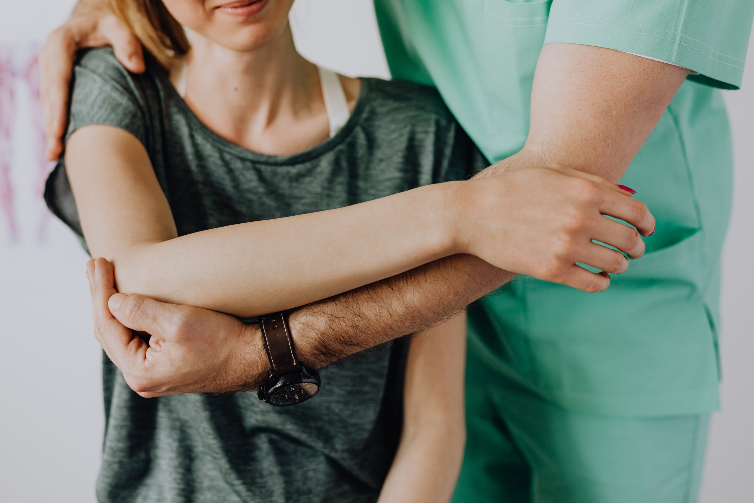 crop unrecognizable orthopedist stretching the shoulder of a female