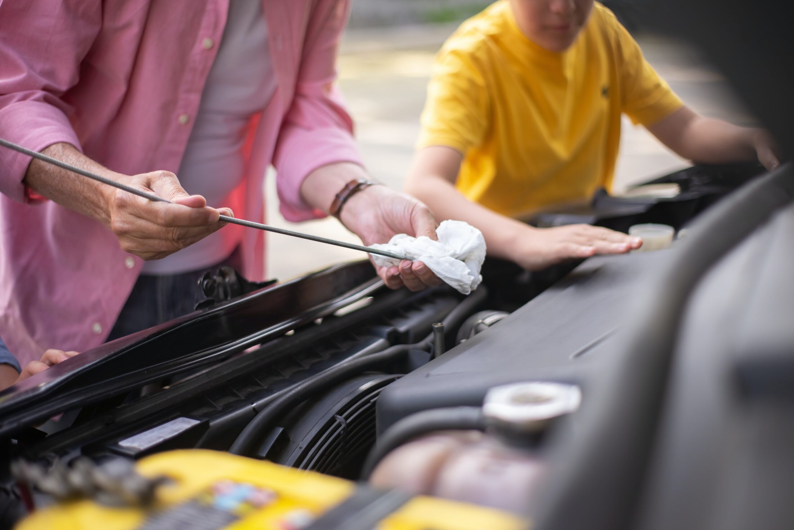 A man checking the oil of a car engine