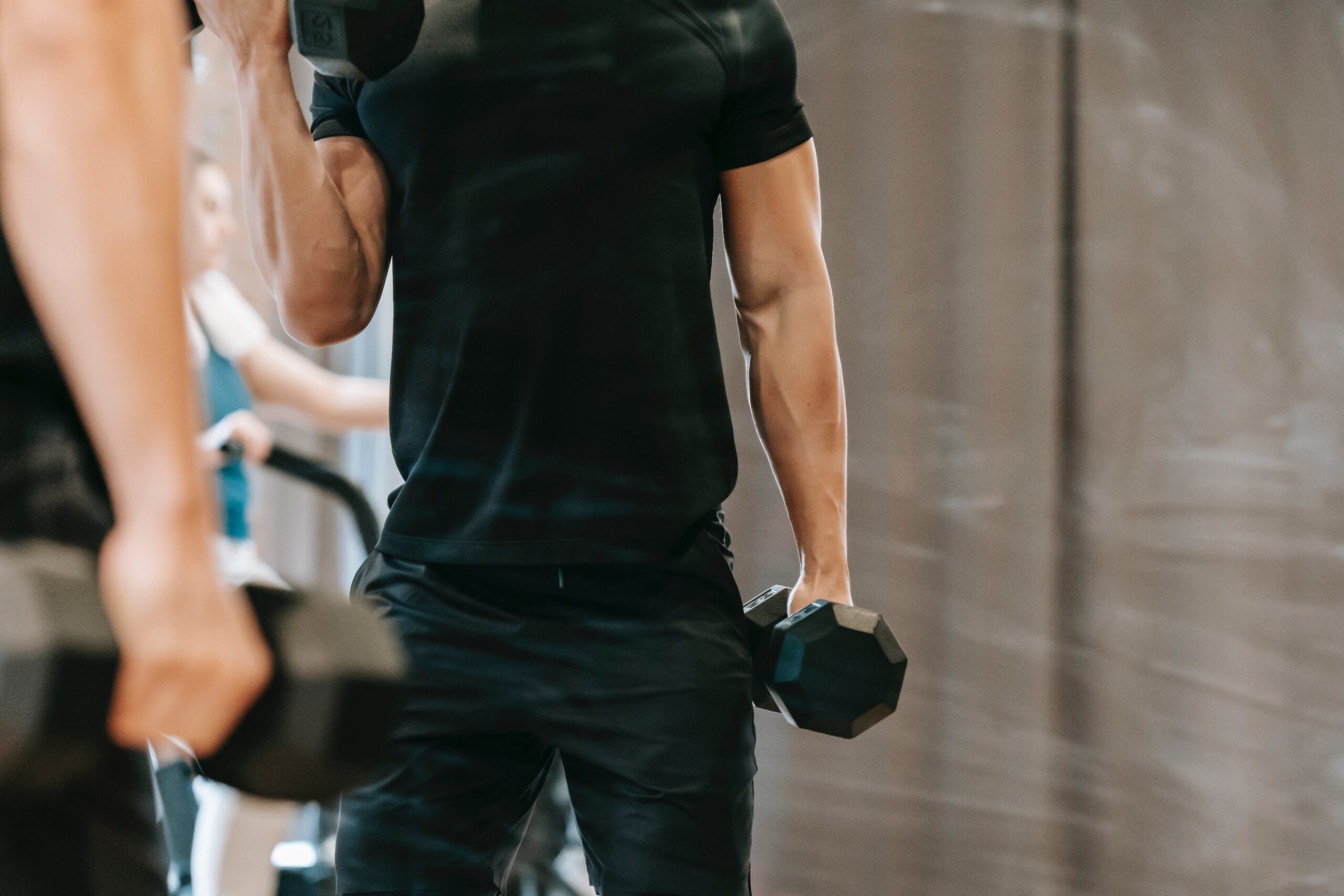 crop sportsman lifting dumbbells during training