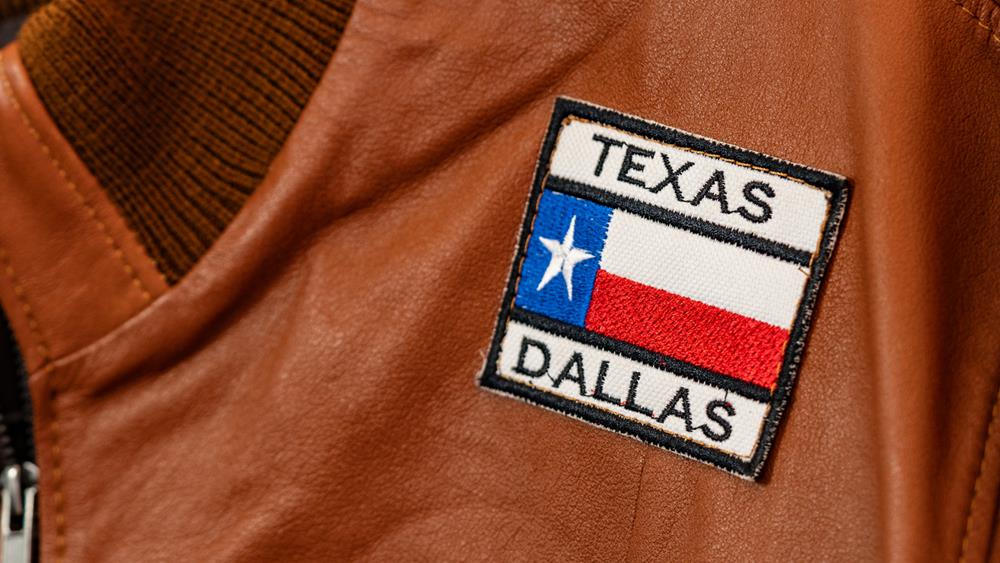 A close-up of a Texas Dallas embroidered patch on a brown leather jacket