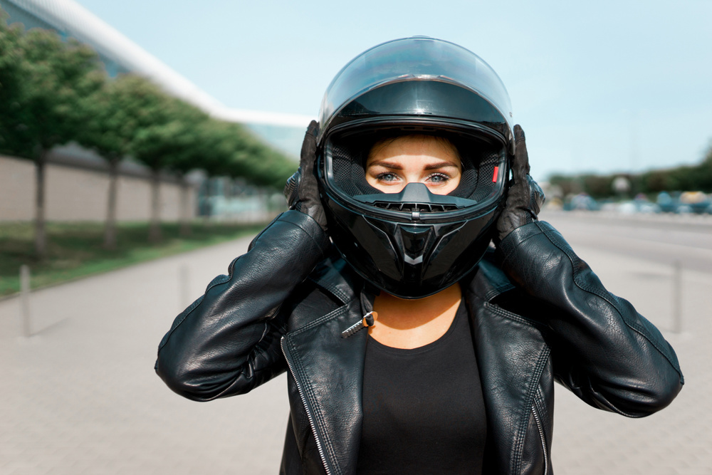 Woman wearing helmet before riding a motorbike. Woman in a Motorcycle with helmet and gloves is an important protective clothing