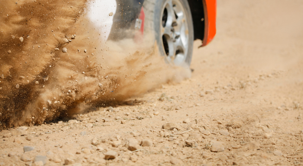 Sand splashing from rally racing car on dirt track