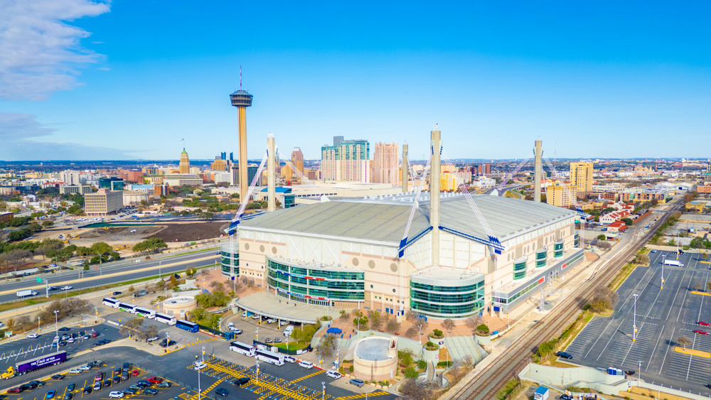 Wide aerial view of the Alamodome surrounded by highways and downtown San Antonio