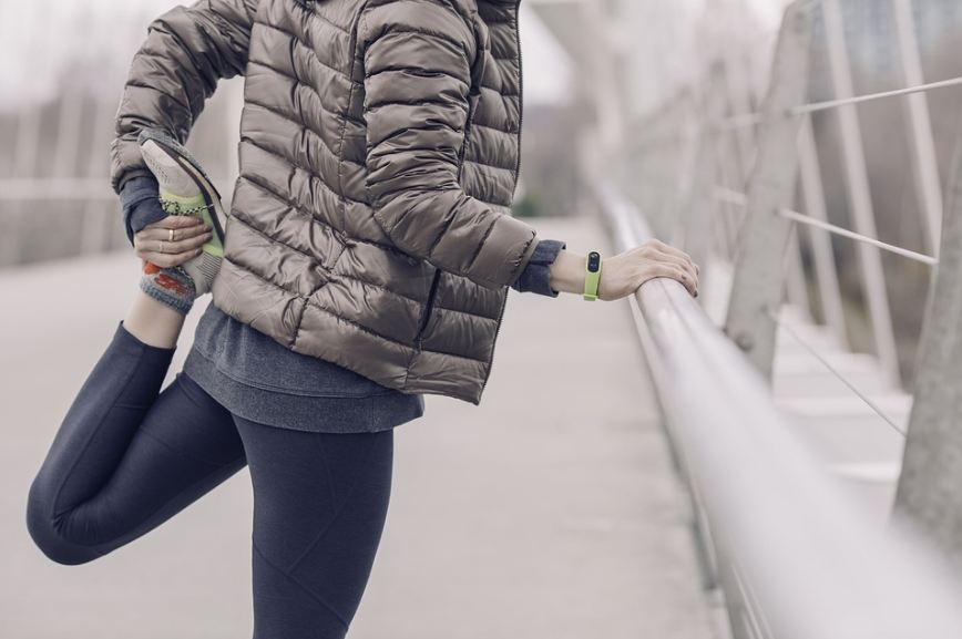 a woman in jacket stretches her leg