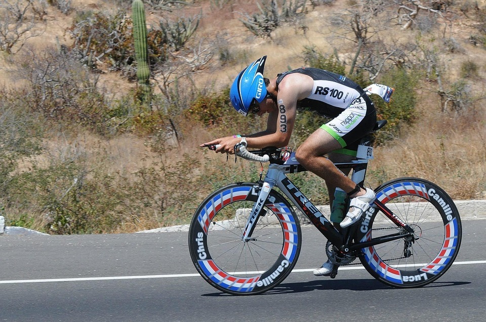 a triathlete in blue helmet and black jersey riding his bike