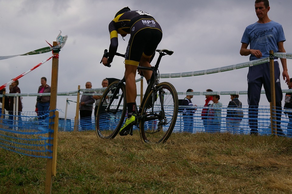 a cyclist in a cyclocross pedaling his bike with spectators nearby