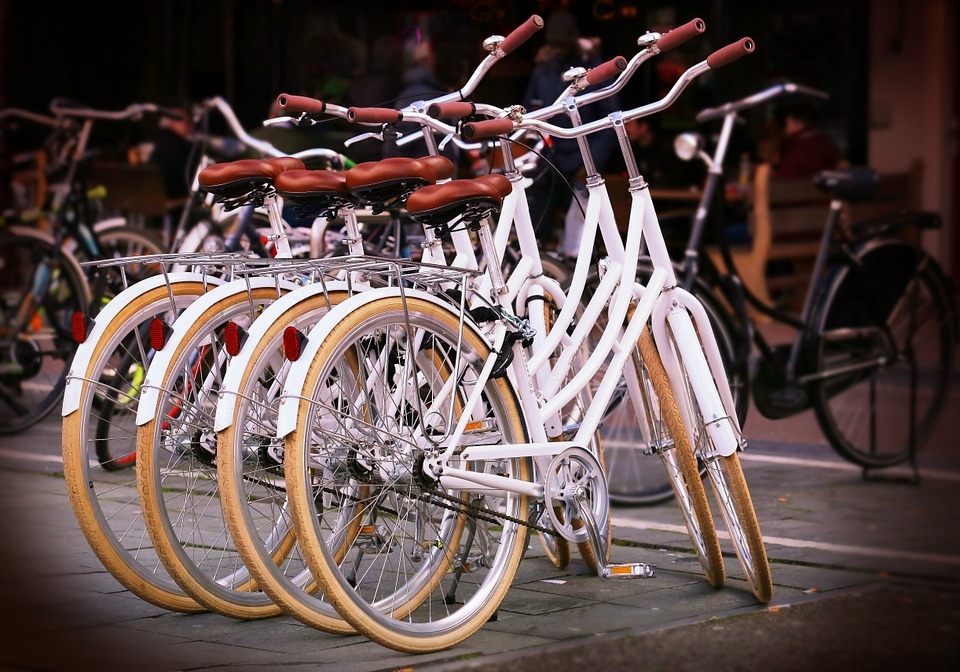 four white bikes in a row with other bikes from their background