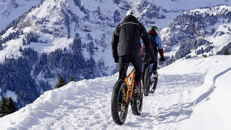 two men biking at a snowy mountain area