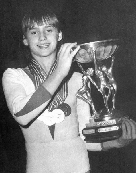 black and white photo of Nadia Comăneci holding a large trophy