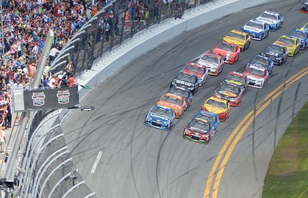 cars racing on the track with thousands of people watching
