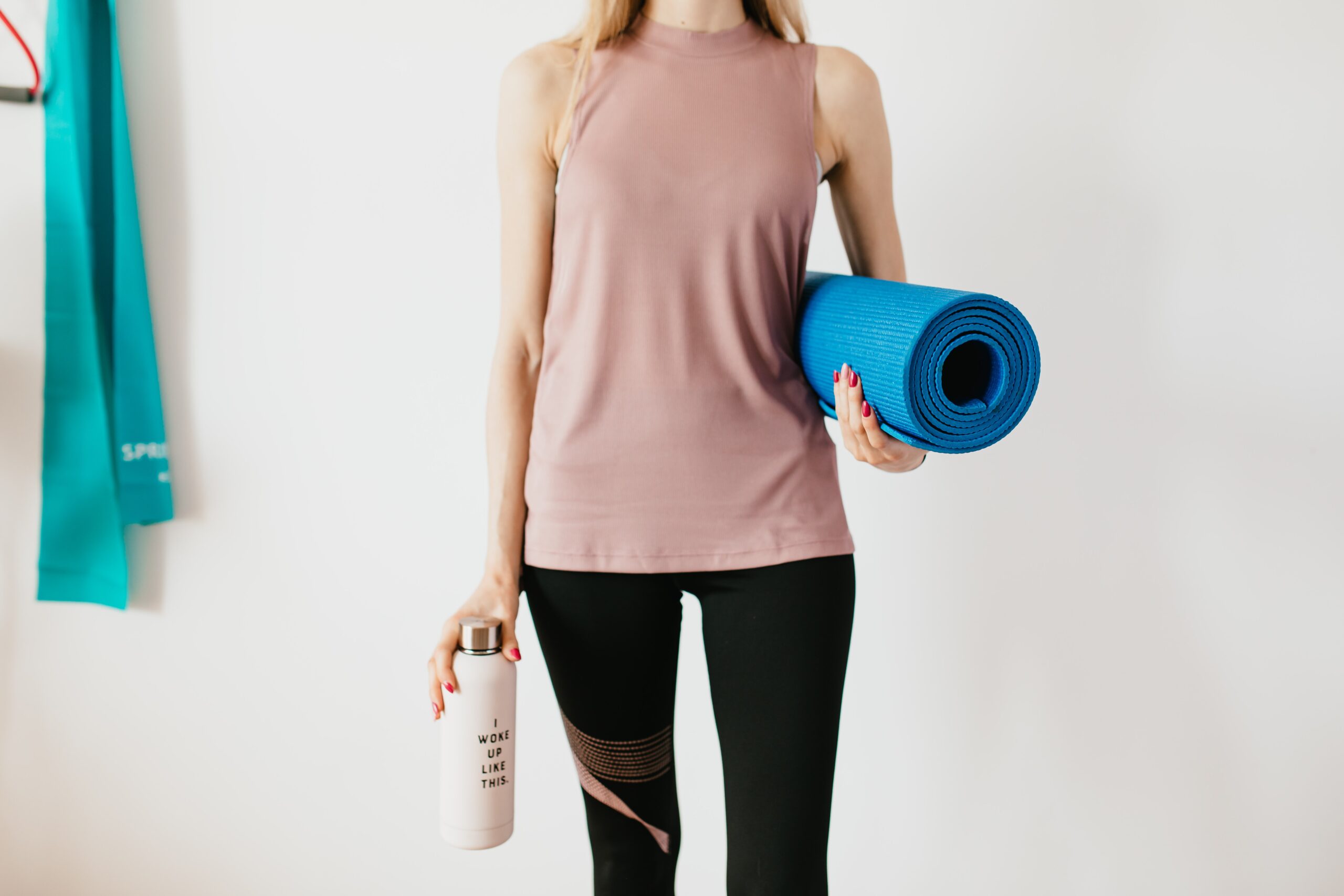 crop sportswoman carrying sports mat and a bottle of water before exercising 