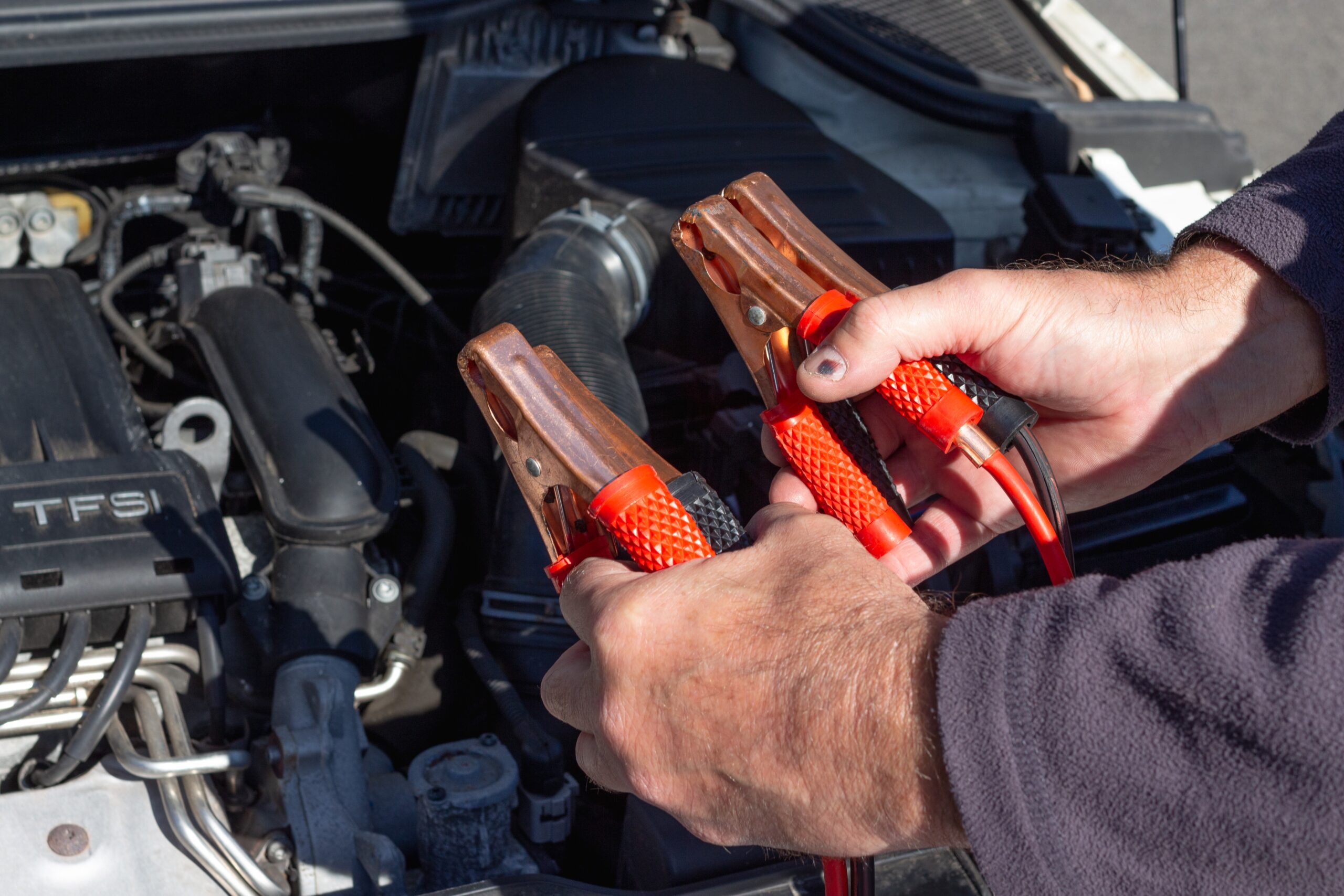 man holding clips in front of a car engine